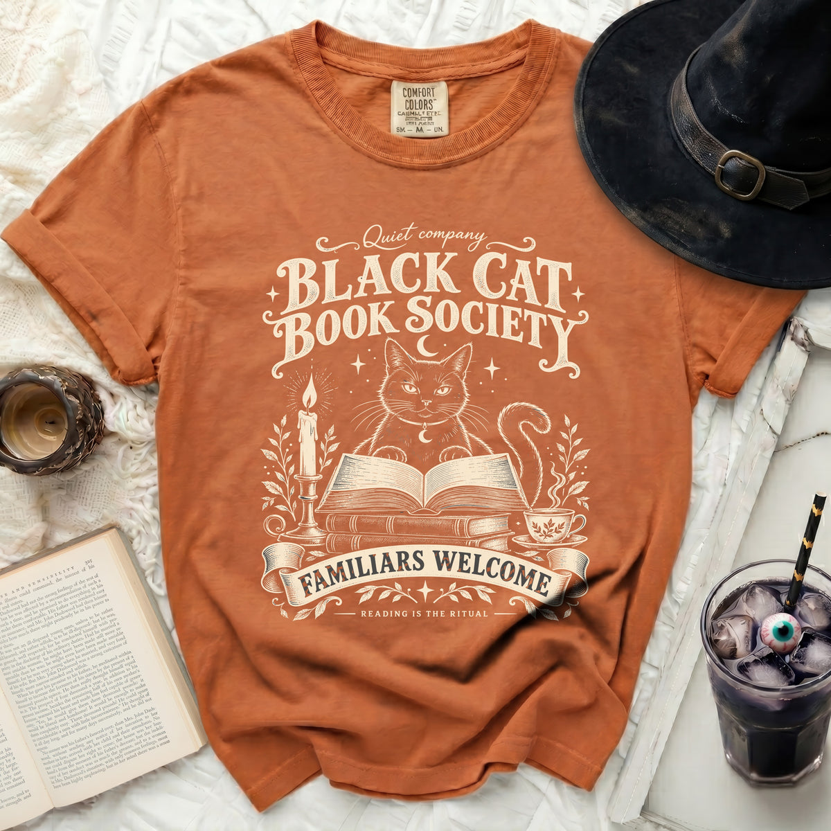 Orange t-shirt with "Black Cat Book Society" and witchy graphics.