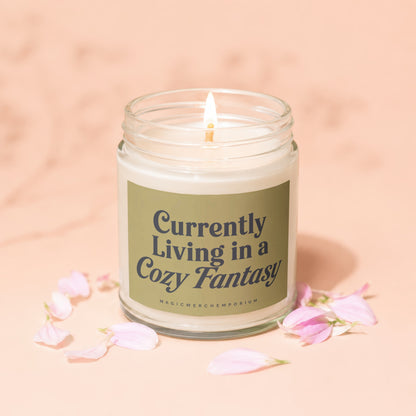 Candle with text "Currently Living in a Cozy Fantasy" and brand "MAGICMERCHTEMPORIUM".