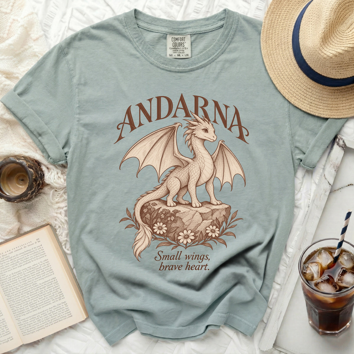 Light blue t-shirt with a dragon design and text "ANDARNA" and "Small wings, brave heart."
