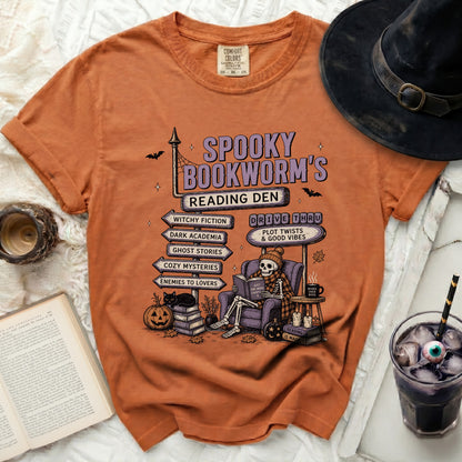 Orange t-shirt with "Spooky Bookworm's Reading Den" graphic, skeleton reading.