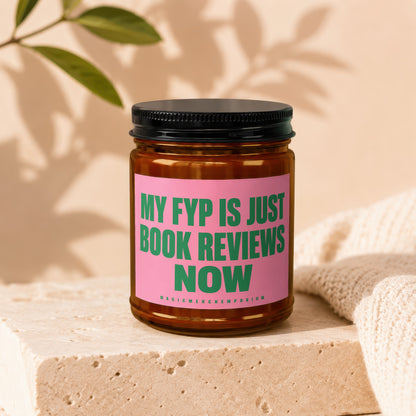 Amber jar candle with pink label reading "MY FYP IS JUST BOOK REVIEWS NOW".