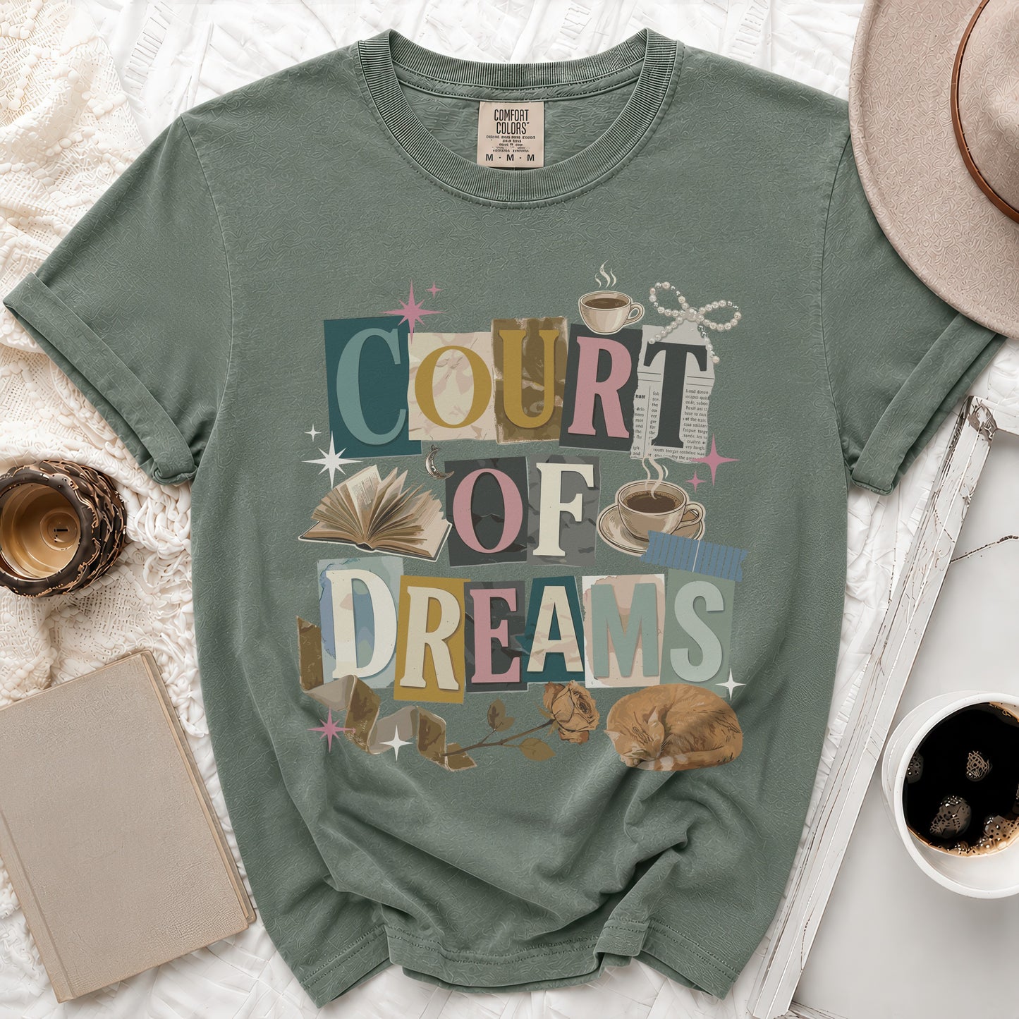 Sage t-shirt with "COURT OF DREAMS" text, books, coffee, and cat.