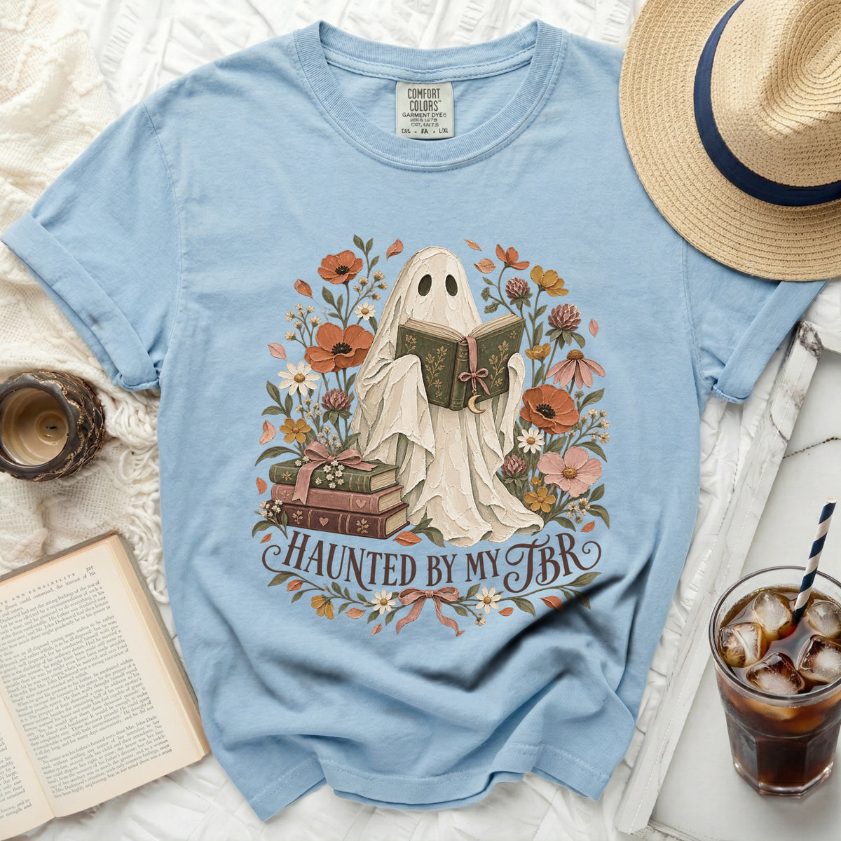 Light blue t-shirt with ghost reading "Haunted by my TBR" among flowers.
