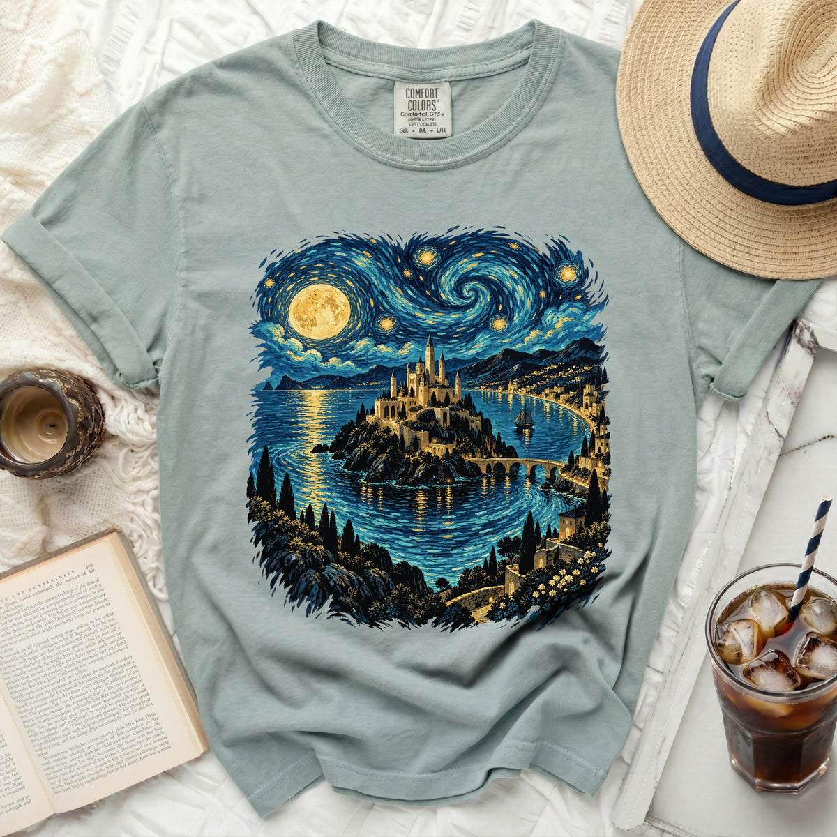 Light blue t-shirt featuring a castle on an island under a swirling starry sky.