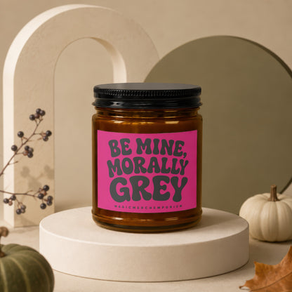 Amber jar candle with pink label: "Be Mine, Morally Grey" and "MagicMerchEmporium."