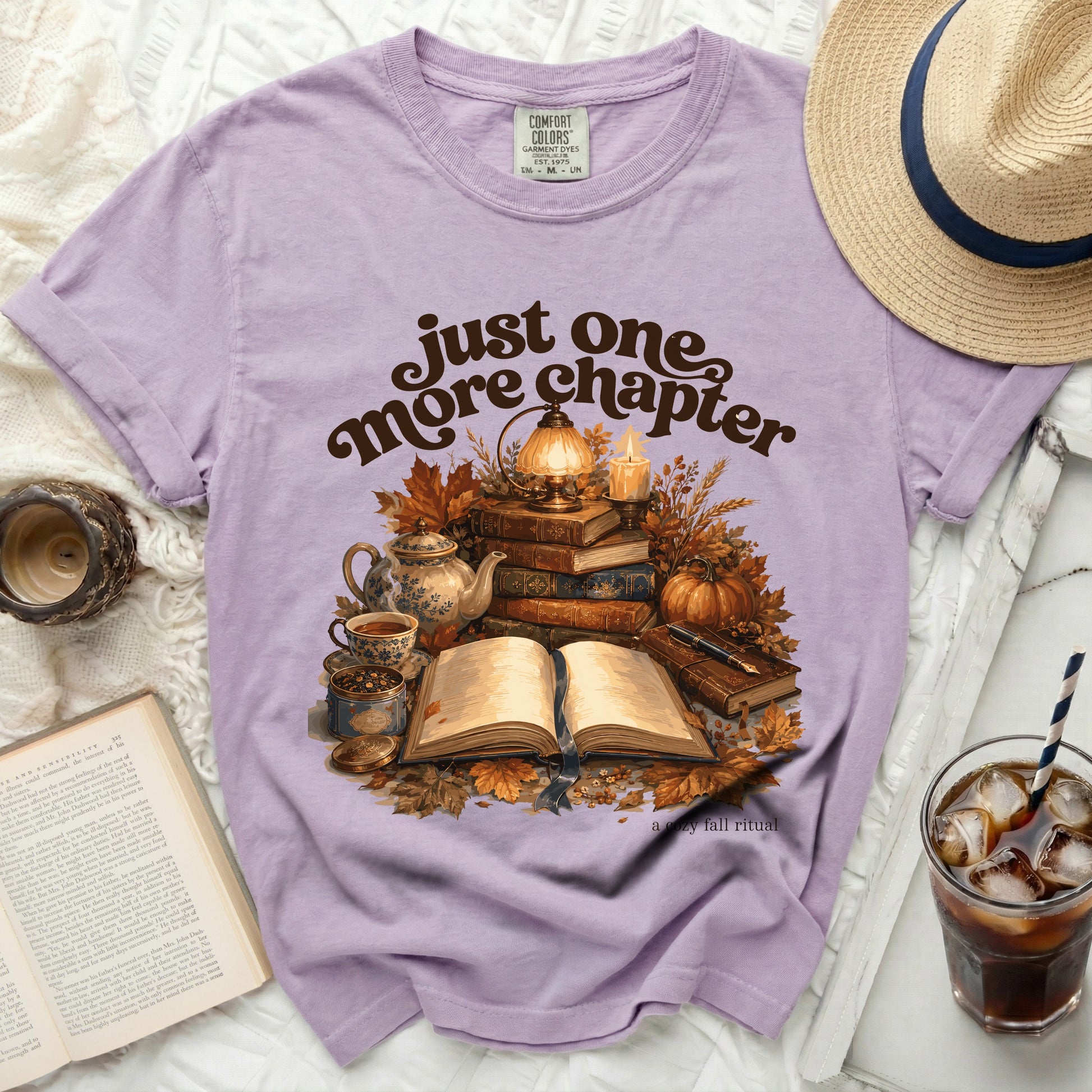 Purple t-shirt with "just one more chapter" and fall illustration.