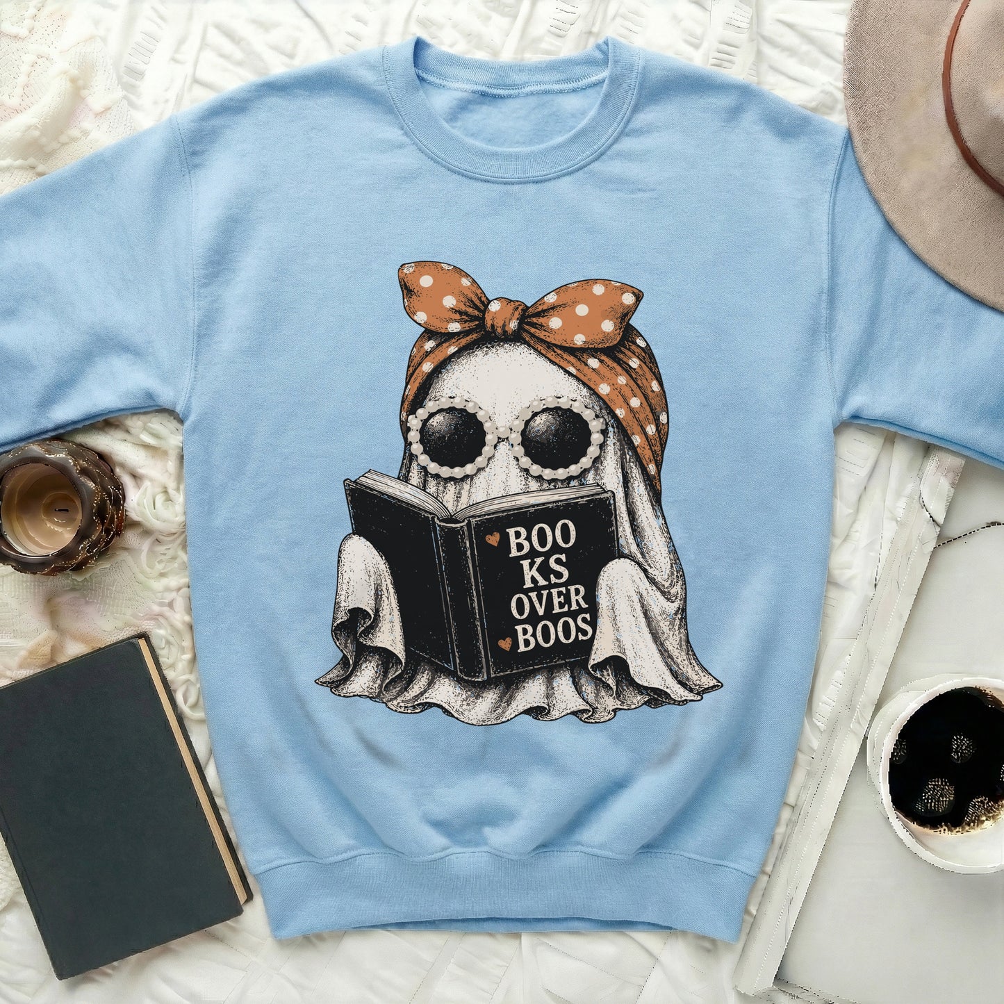 Light blue sweatshirt with a ghost reading a book that says "BooKs Over Boos".