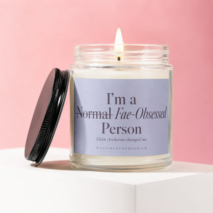Glass jar candle with lit wick, black lid, and label: "I'm a Normal Fae-Obsessed Person"