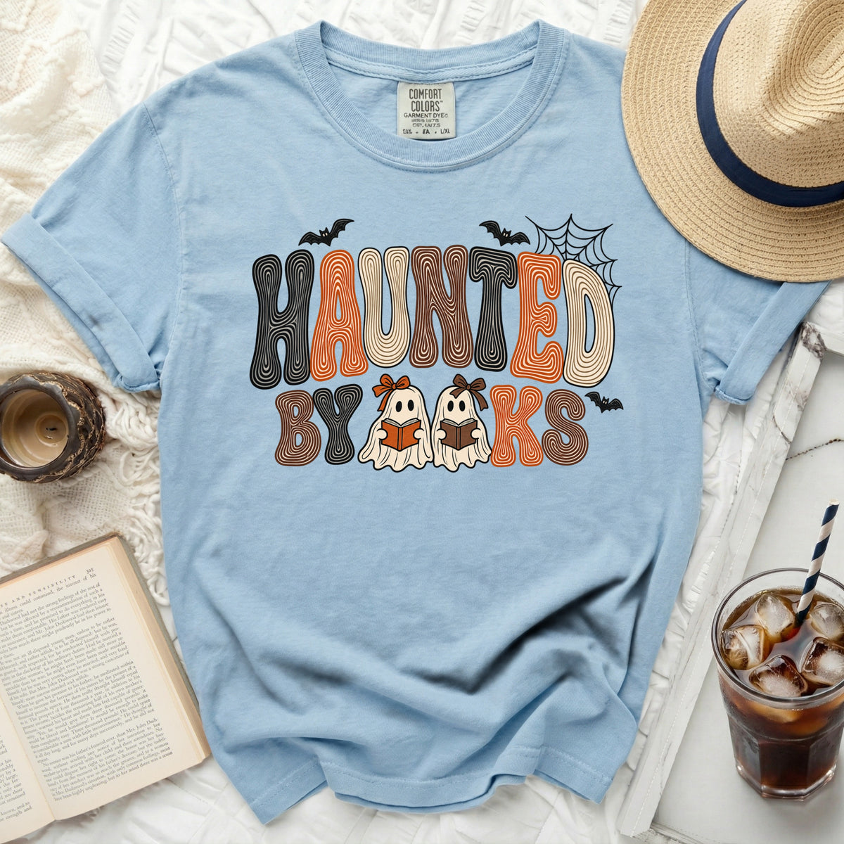 Light blue t-shirt with "Haunted by Books" graphic featuring ghosts reading books.