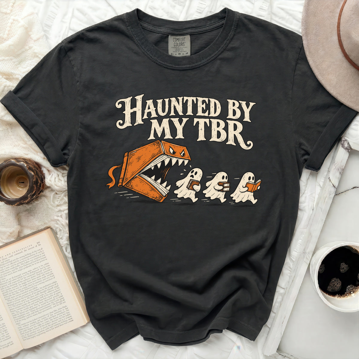 Dark t-shirt with "Haunted By My TBR" graphic of a book monster chasing ghosts.