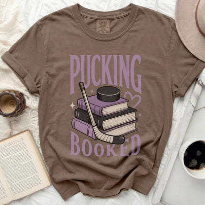 Brown t-shirt with "Pucking Booked" text and stacked books with hockey puck.