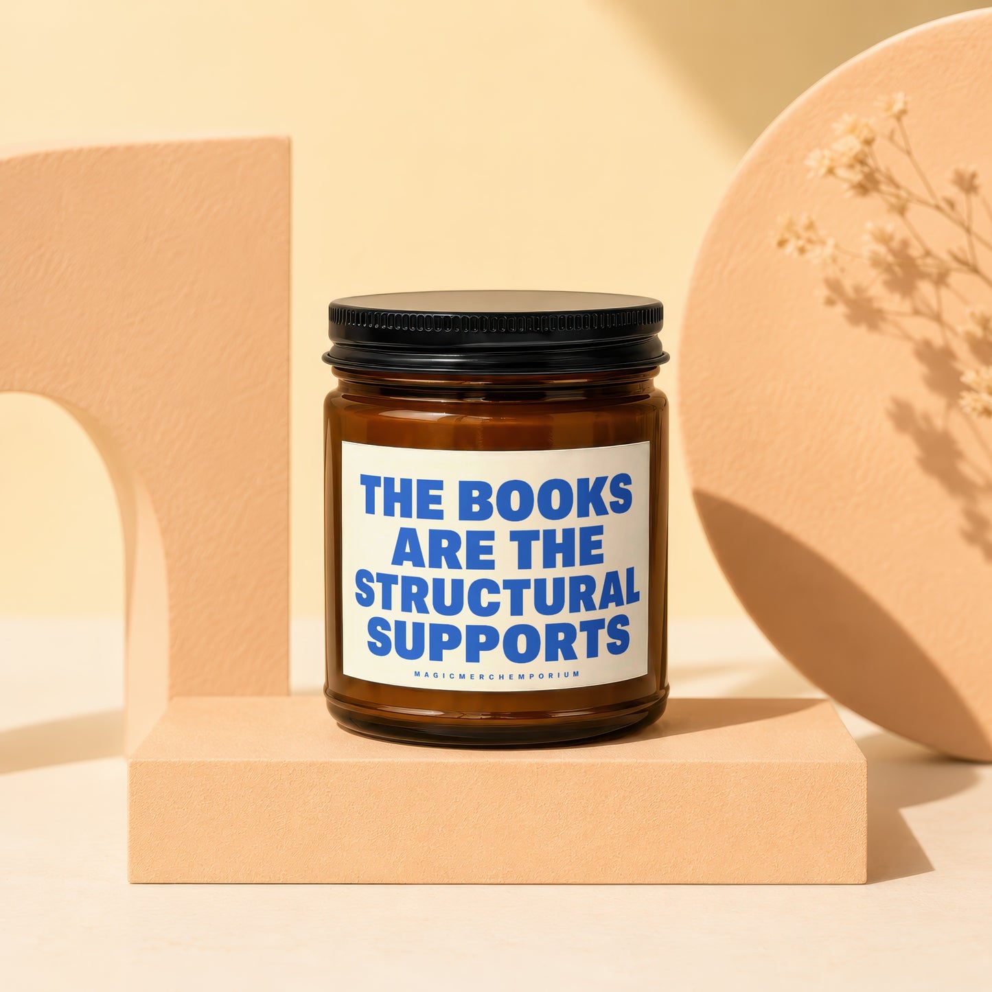 Amber glass candle with blue text "THE BOOKS ARE THE STRUCTURAL SUPPORTS".