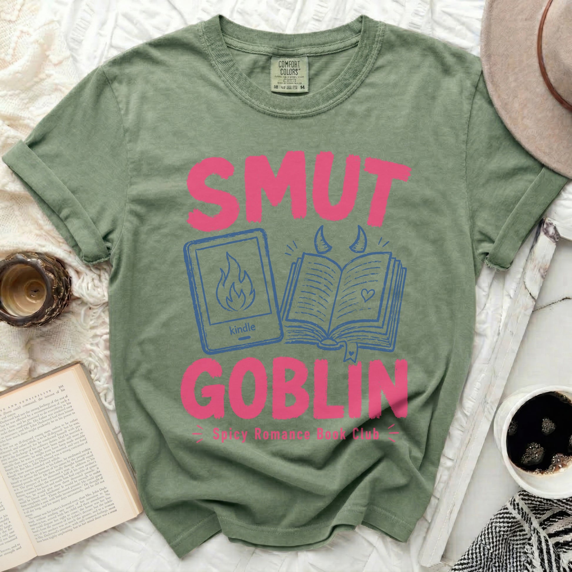 Green t-shirt with pink text "SMUT GOBLIN" and Kindle/book graphic.