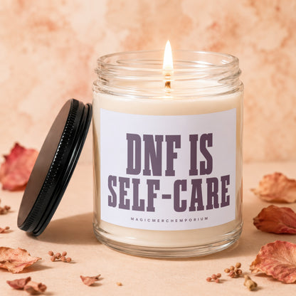 Glass jar candle burning with text "DNF IS SELF-CARE" on label.