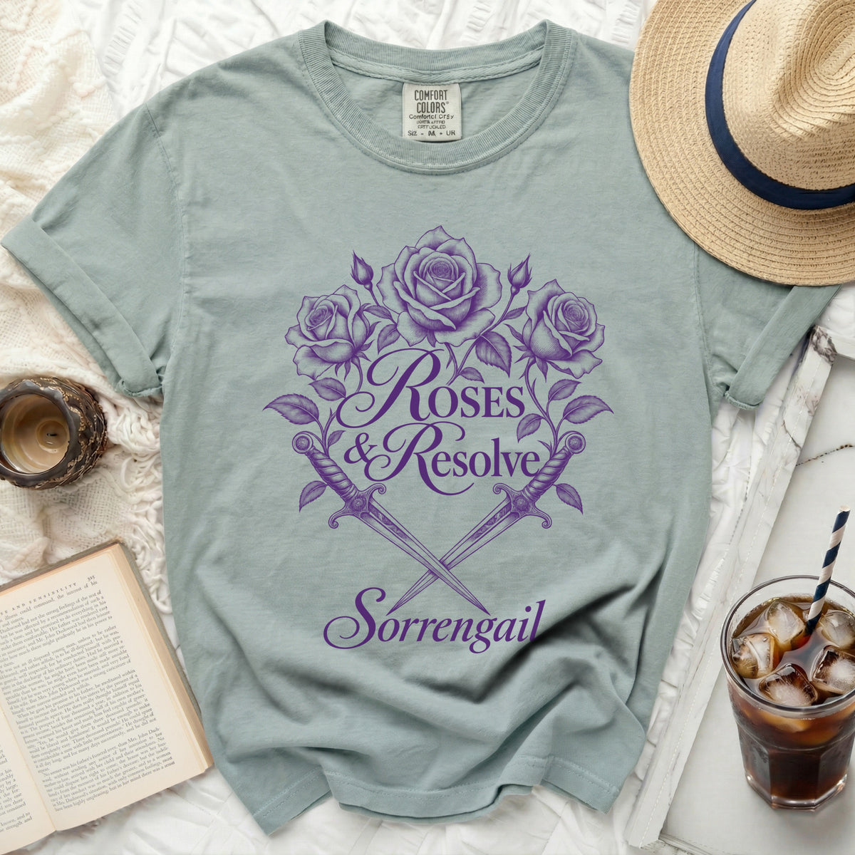 Light blue t-shirt with purple roses, crossed daggers, and text "Roses & Resolve Sorrengail".