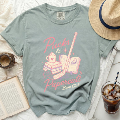 Pink ice skates, books, and coffee cup with "Puck & Papercuts Book Club" text.