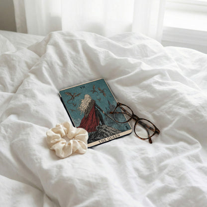 Tarot card, glasses, and scrunchie on white linens.
