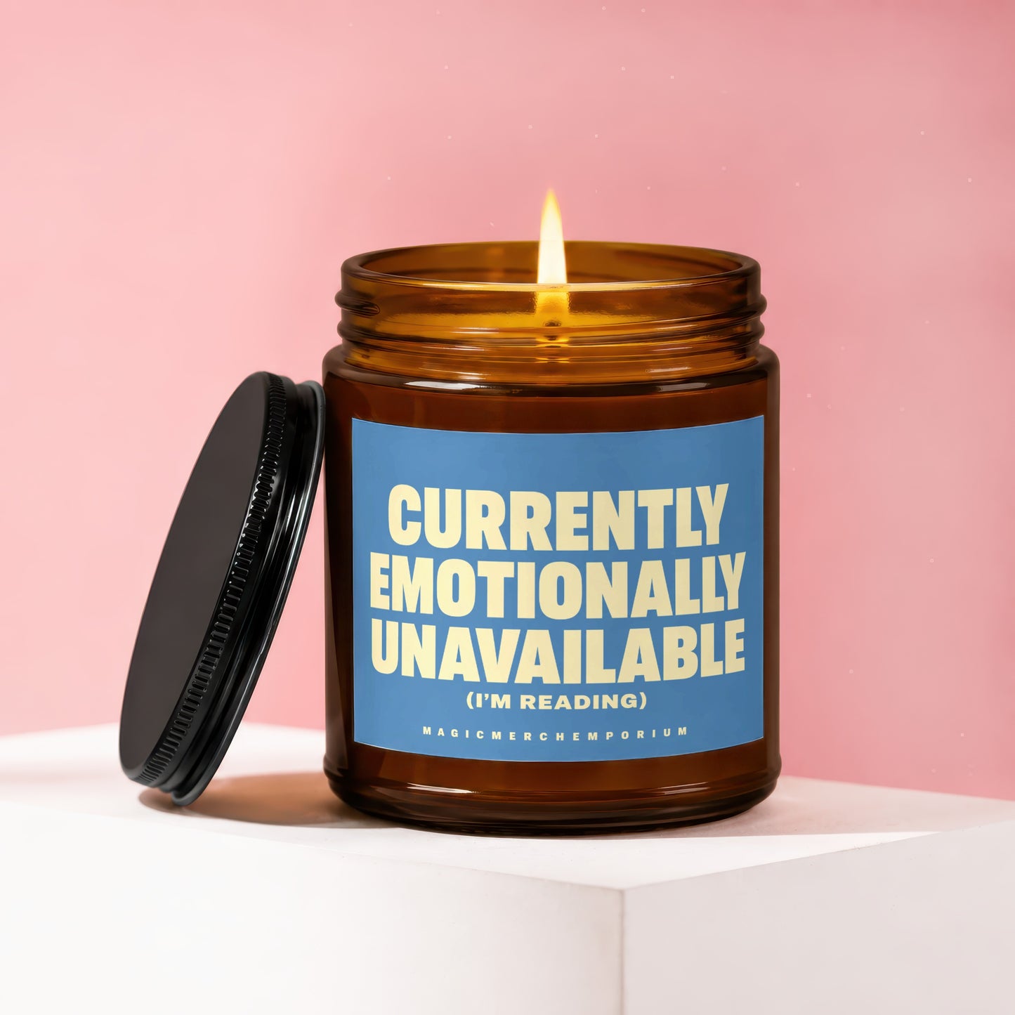 Amber jar candle with lit flame and blue label reading "Currently Emotionally Unavailable (I'm Reading)".
