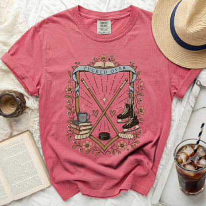 Pink t-shirt with "Pucked Over" text, hockey sticks, skates, and books.