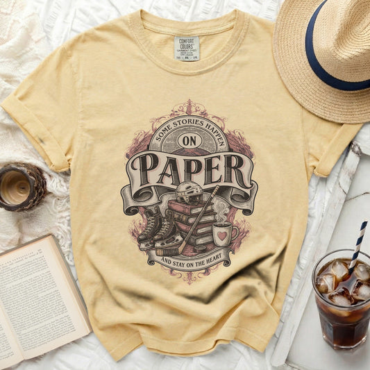 Yellow t-shirt with "Some Stories Happen On Paper" text and hockey gear graphic.