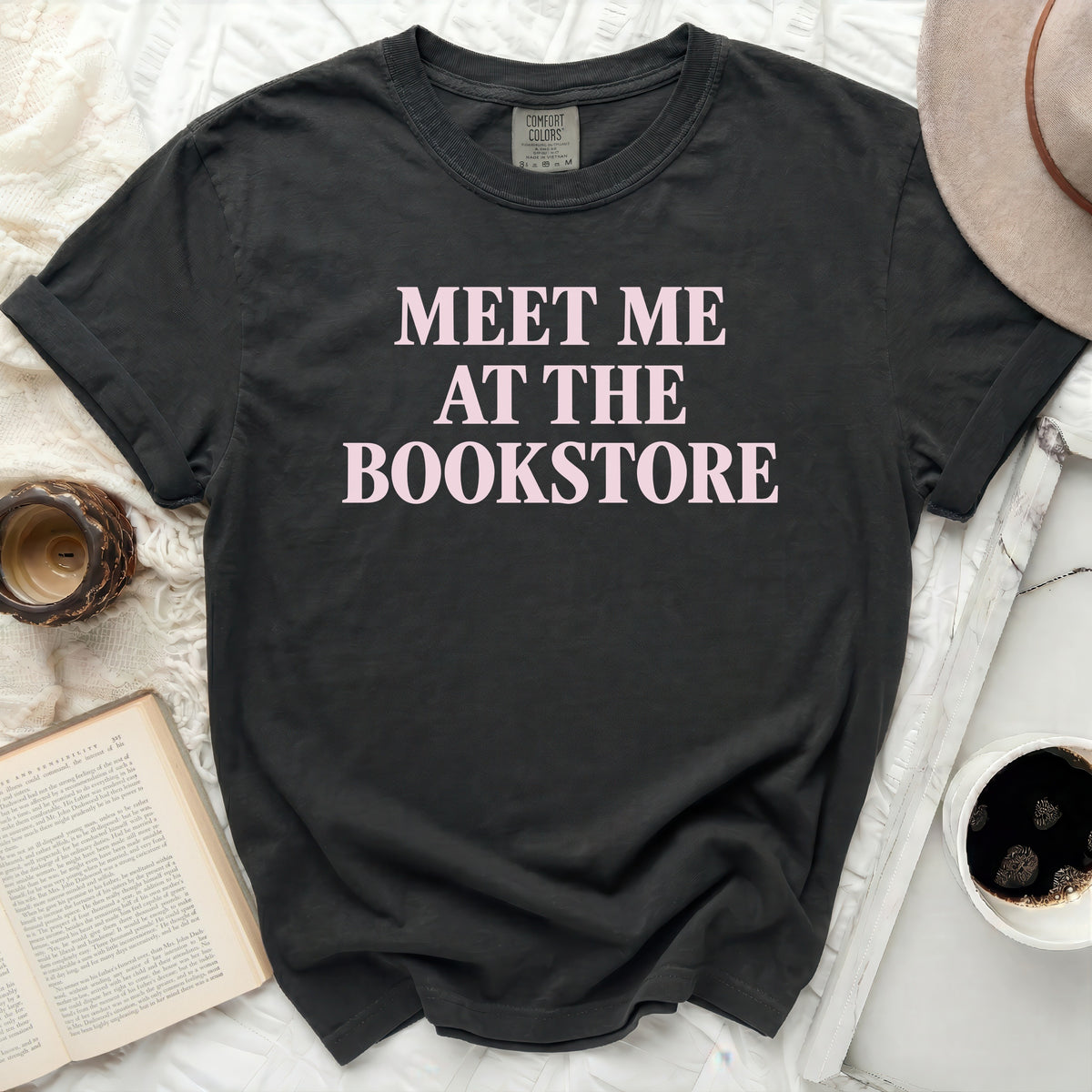 Dark t-shirt with pink text "MEET ME AT THE BOOKSTORE"