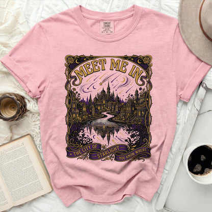 Pink t-shirt with a gold, purple, and pink graphic of a city and stars.