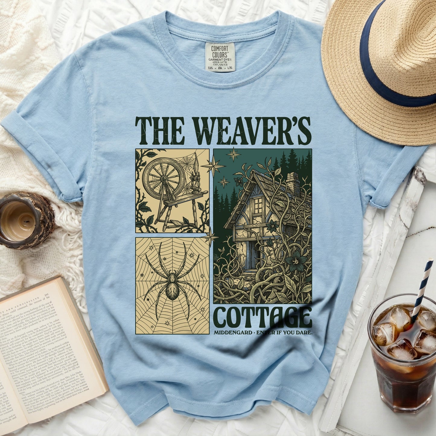 Light blue t-shirt with "The Weaver's Cottage" graphic featuring a spinning wheel, cottage, and spider.