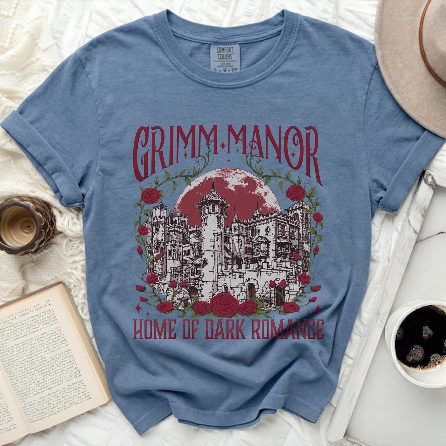 Blue t-shirt with "Grimm Manor Home of Dark Romance" gothic print.