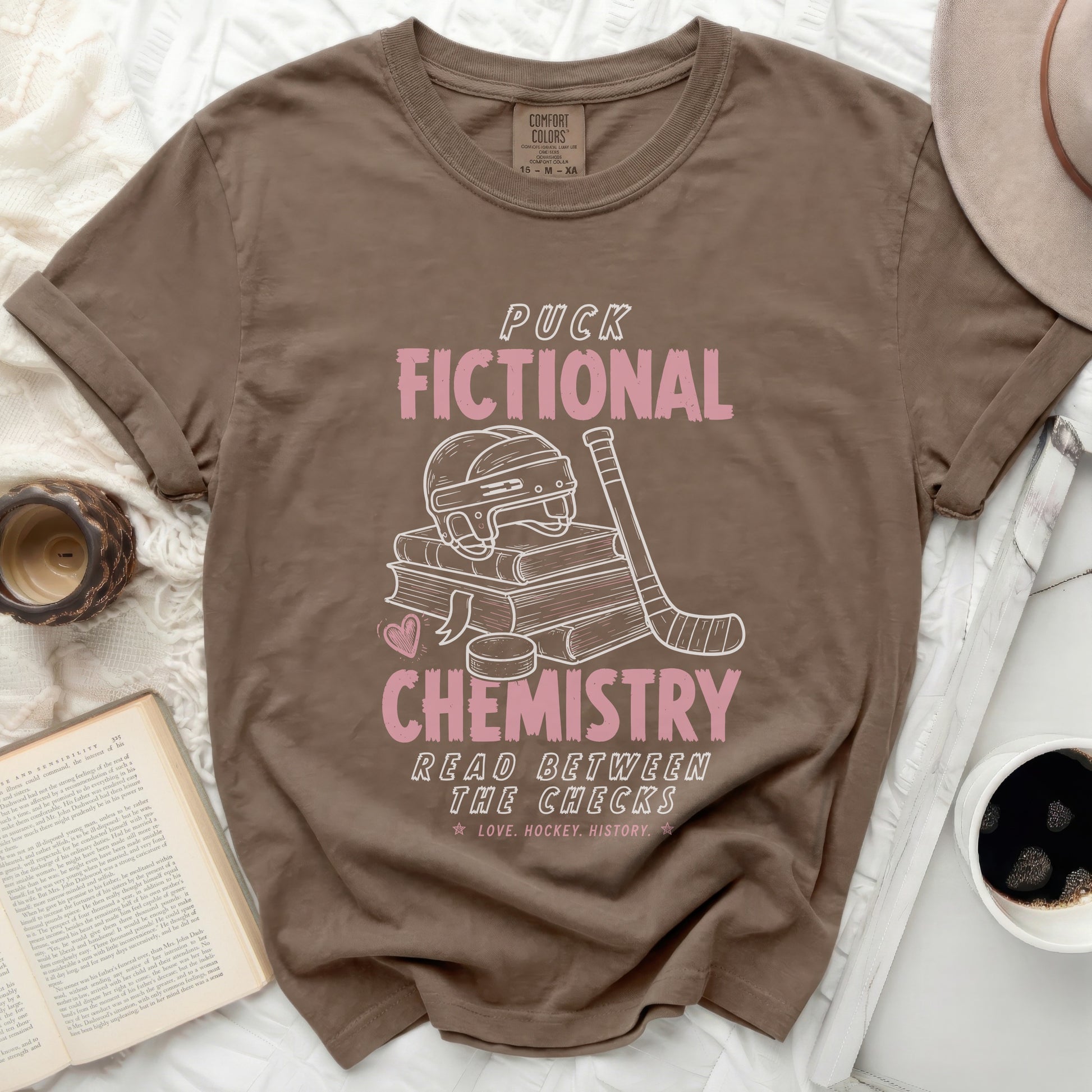 Brown t-shirt with "Puck Chemistry Read Between The Checks" text and hockey graphic.