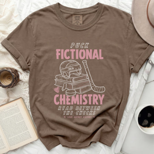 Brown t-shirt with "Puck Chemistry Read Between The Checks" text and hockey graphic.