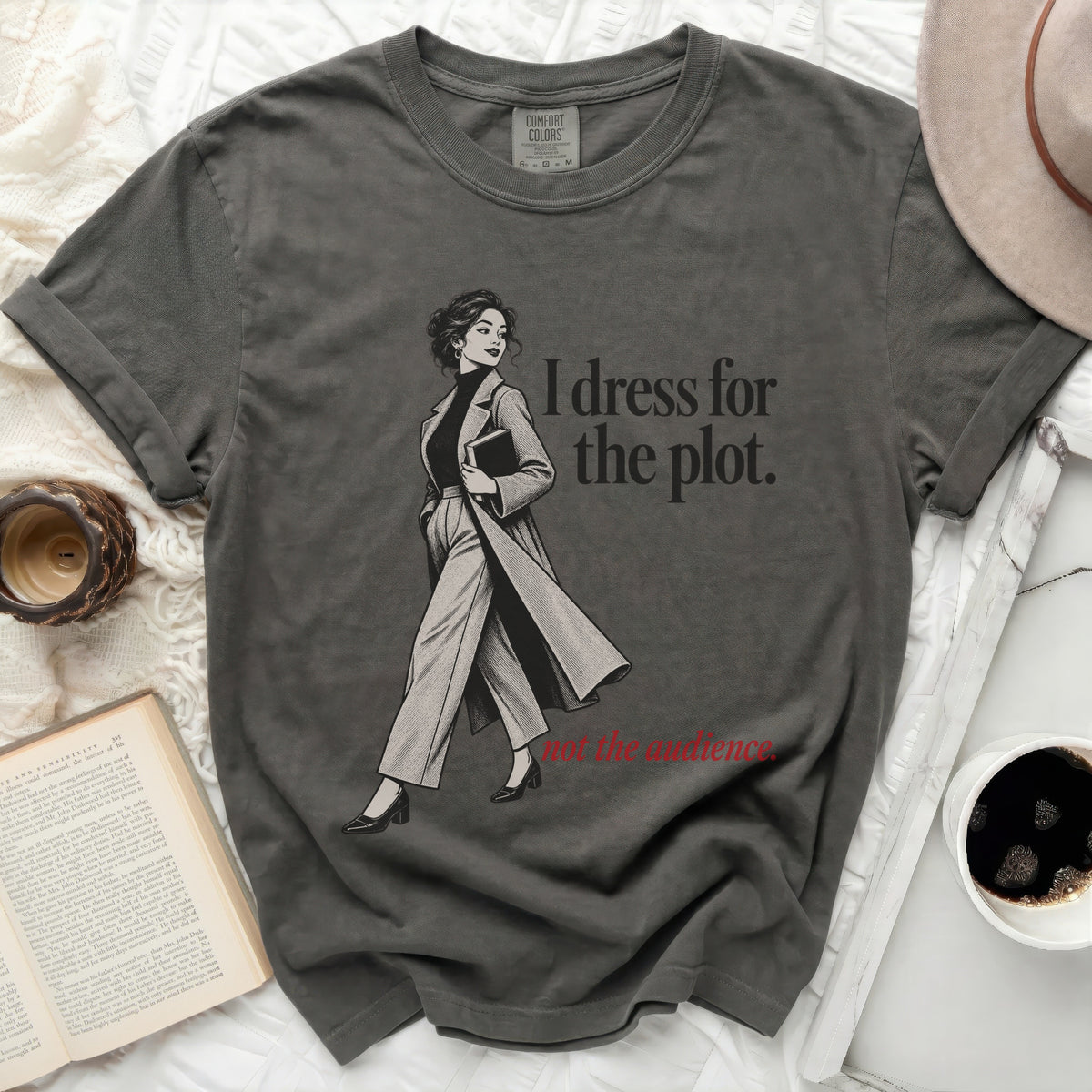 Dark gray t-shirt with graphic of woman and text "I dress for the plot. not the audience."