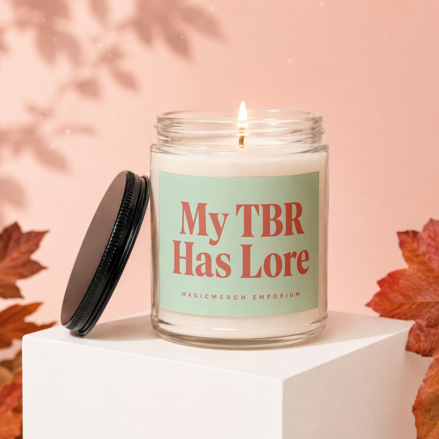 Lit candle in glass jar with "My TBR Has Lore" label and detached lid.