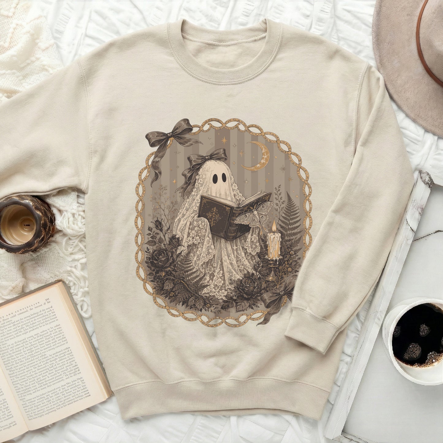 Cream sweatshirt with a vintage ghost reading a book and surrounded by lace, florals, and moths.