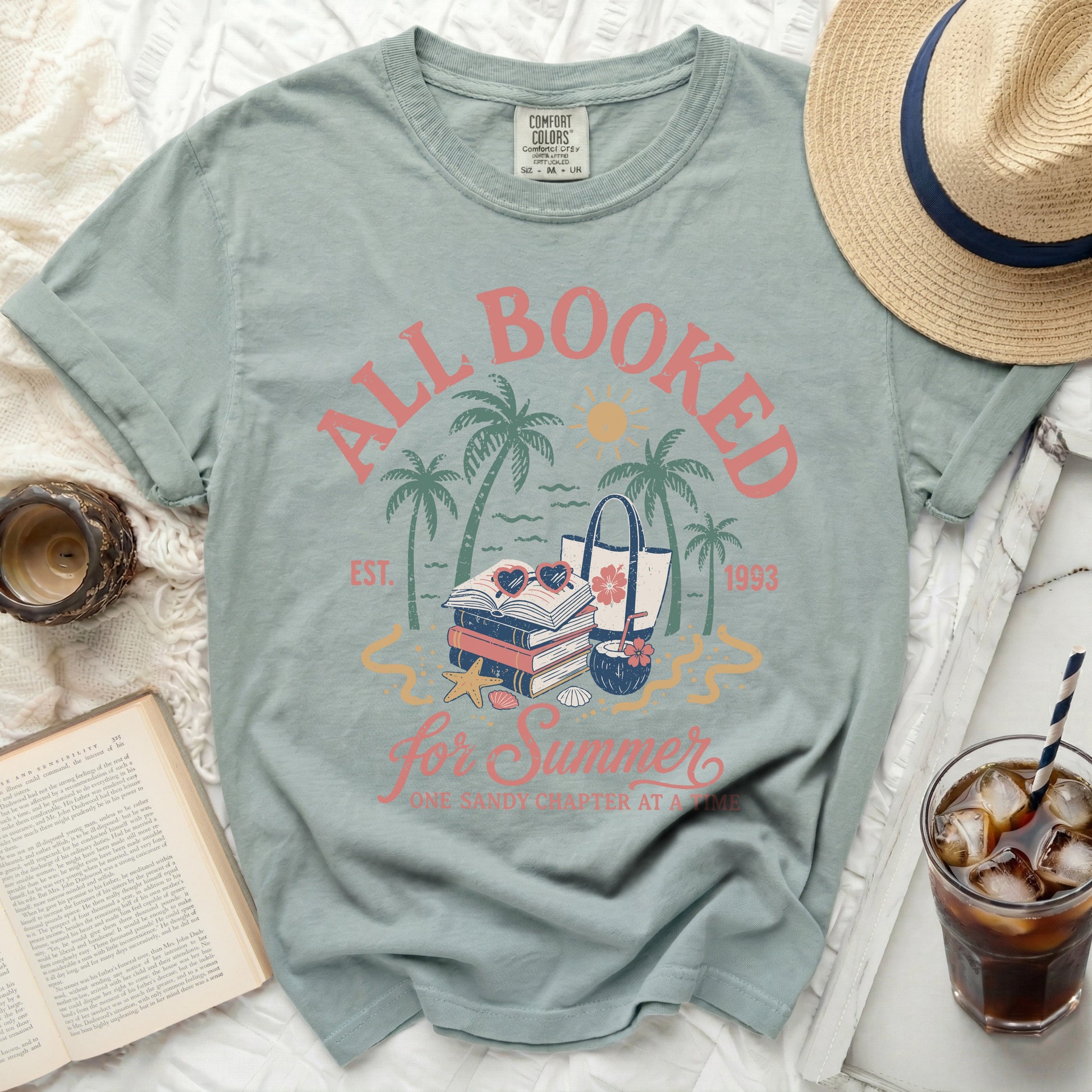 All Booked for Summer graphic tee with books, beach bag, and palm trees.
