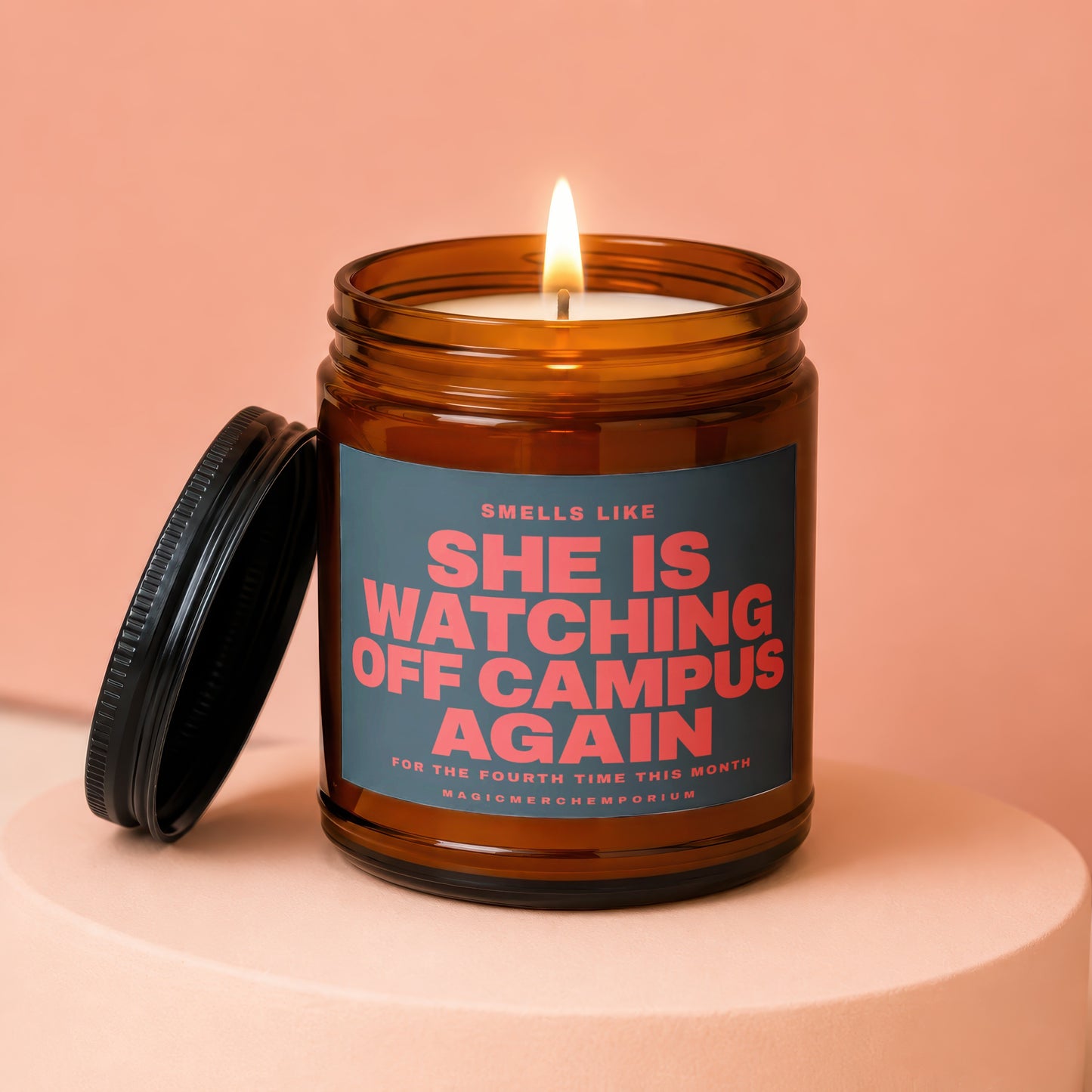 Amber jar candle with lit flame, lid off, and text "SHE IS WATCHING OFF CAMPUS AGAIN".