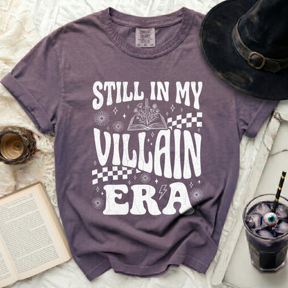 Still in my Villain Era graphic t-shirt with book and sword design.