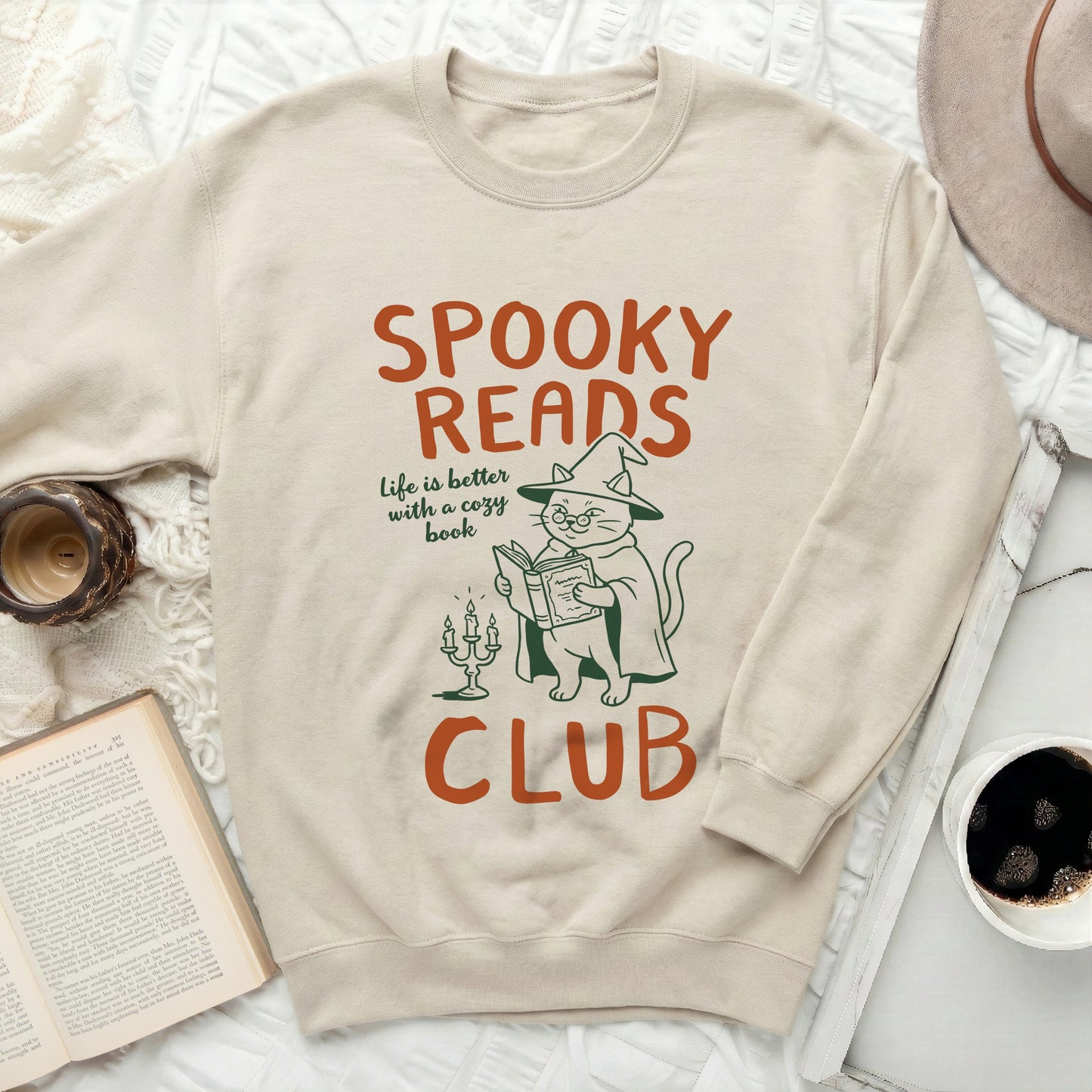 Cream sweatshirt with "Spooky Reads" cat illustration and text.
