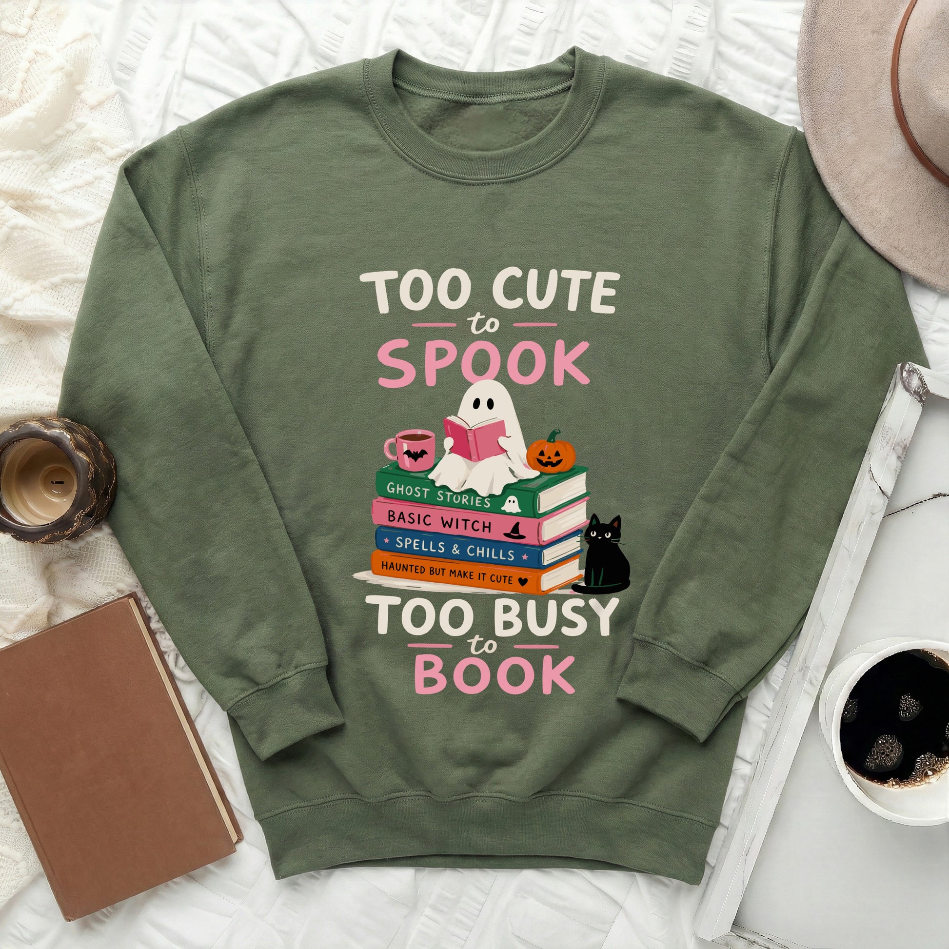 Green crewneck sweatshirt with "Too Cute to Spook" and "Too Busy to Book" text graphics.