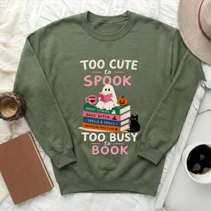 Green crewneck sweatshirt with "Too Cute to Spook" and "Too Busy to Book" text graphics.