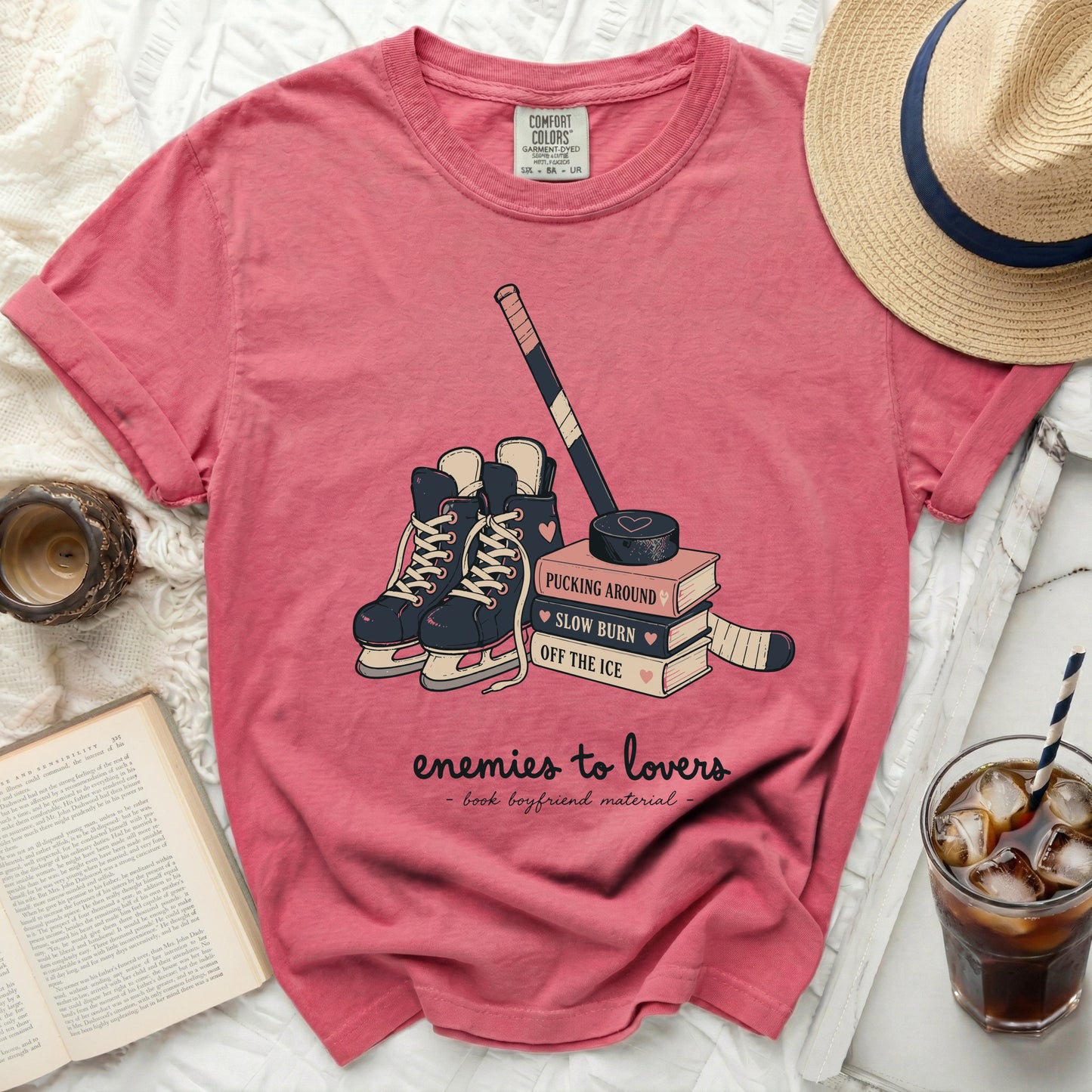 Pink t-shirt with hockey skates, puck, and books with "enemies to lovers" text.
