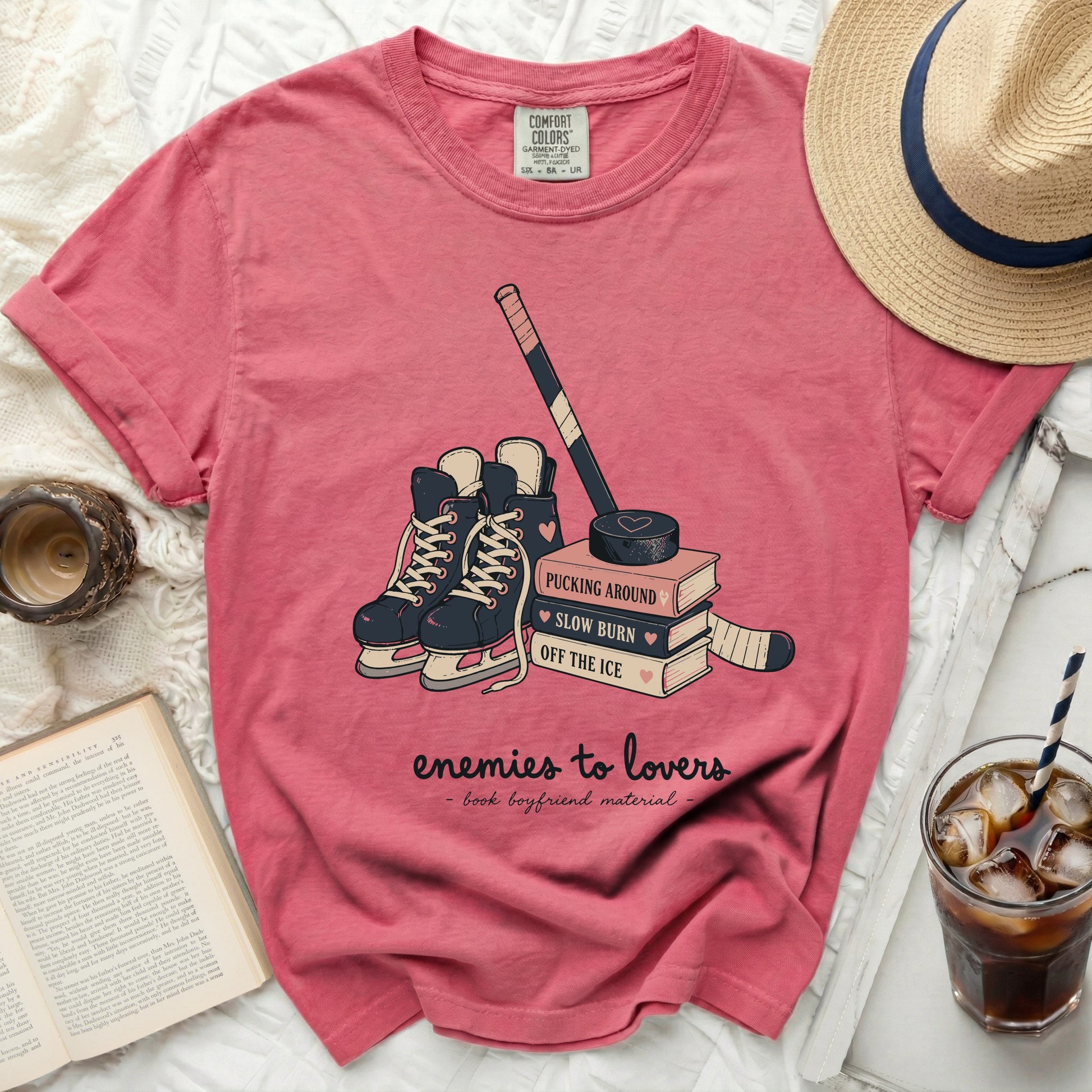 Pink t-shirt with hockey skates, puck, and books with "enemies to lovers" text.