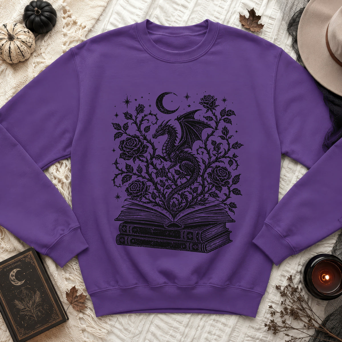 Purple sweatshirt with a black dragon, roses, moon, and stars design on an open book.