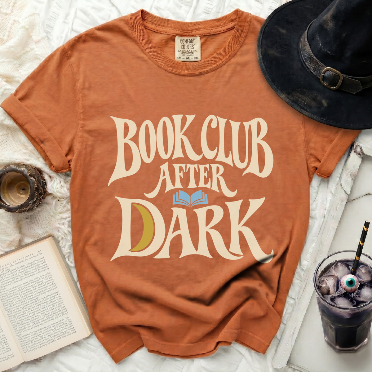 Orange t-shirt with "Book Club After Dark" text, a crescent moon, and an open book graphic.