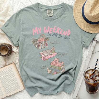 Pastel green t-shirt with "My Weekend Is All Booked" graphic and book illustrations.