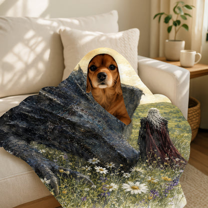 Brown dog peeking from dragon-themed blanket with warrior in a field.
