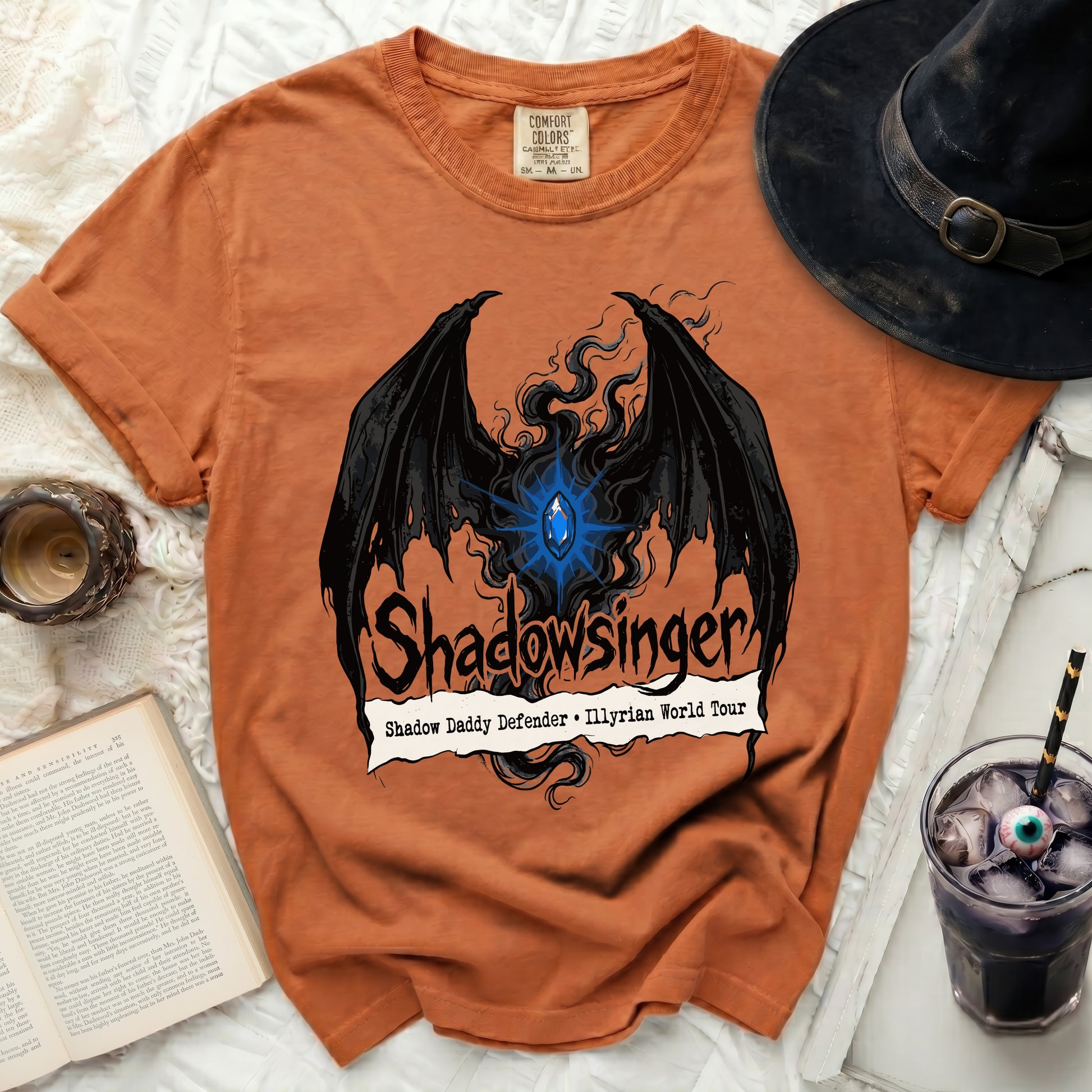 Orange t-shirt with black wings and blue gem graphic, "Shadowsinger," "Shadow Daddy Defender," and "Illyrian World Tour."