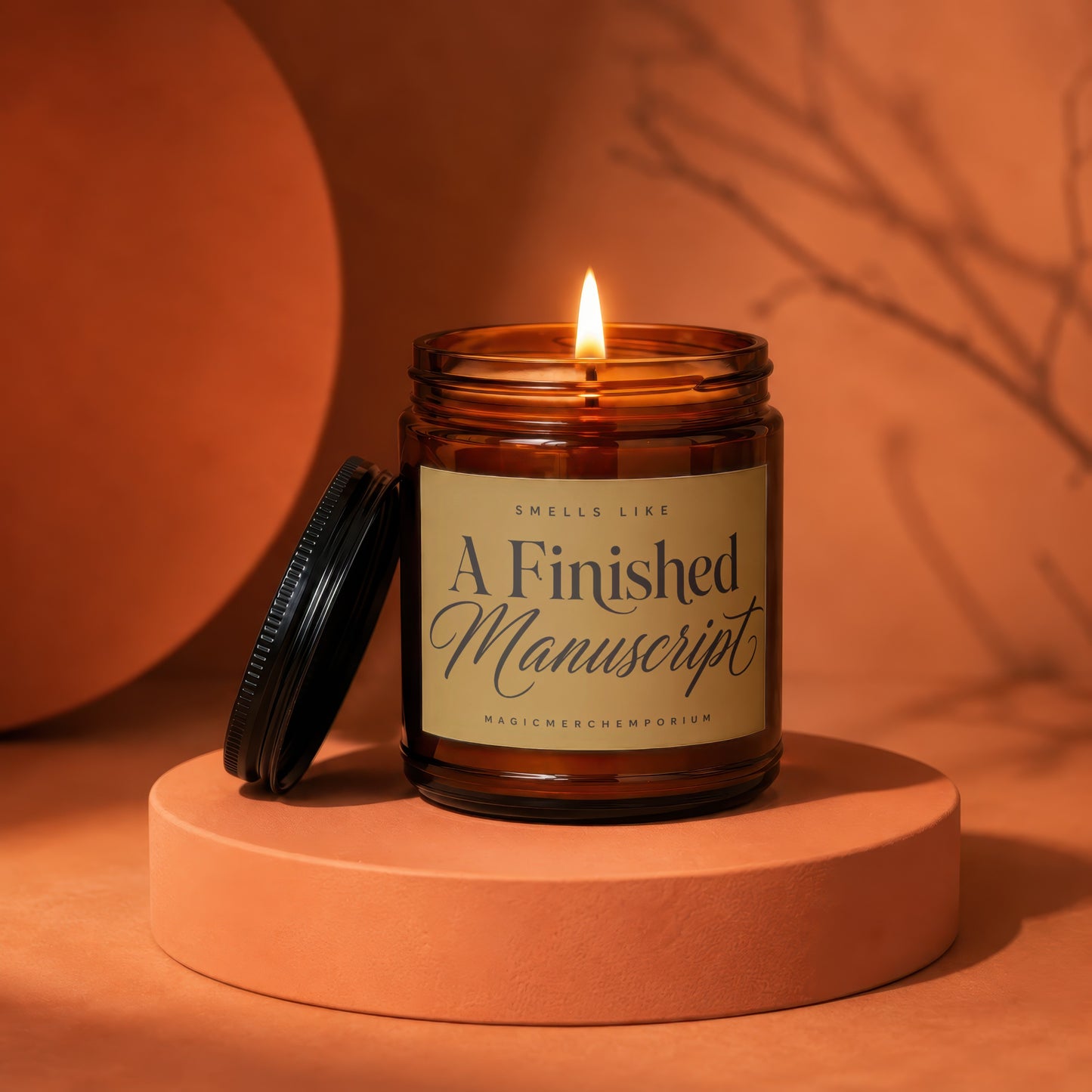 Amber jar candle with lit flame, reads "A Finished Manuscript" and "MAGICMERCH"