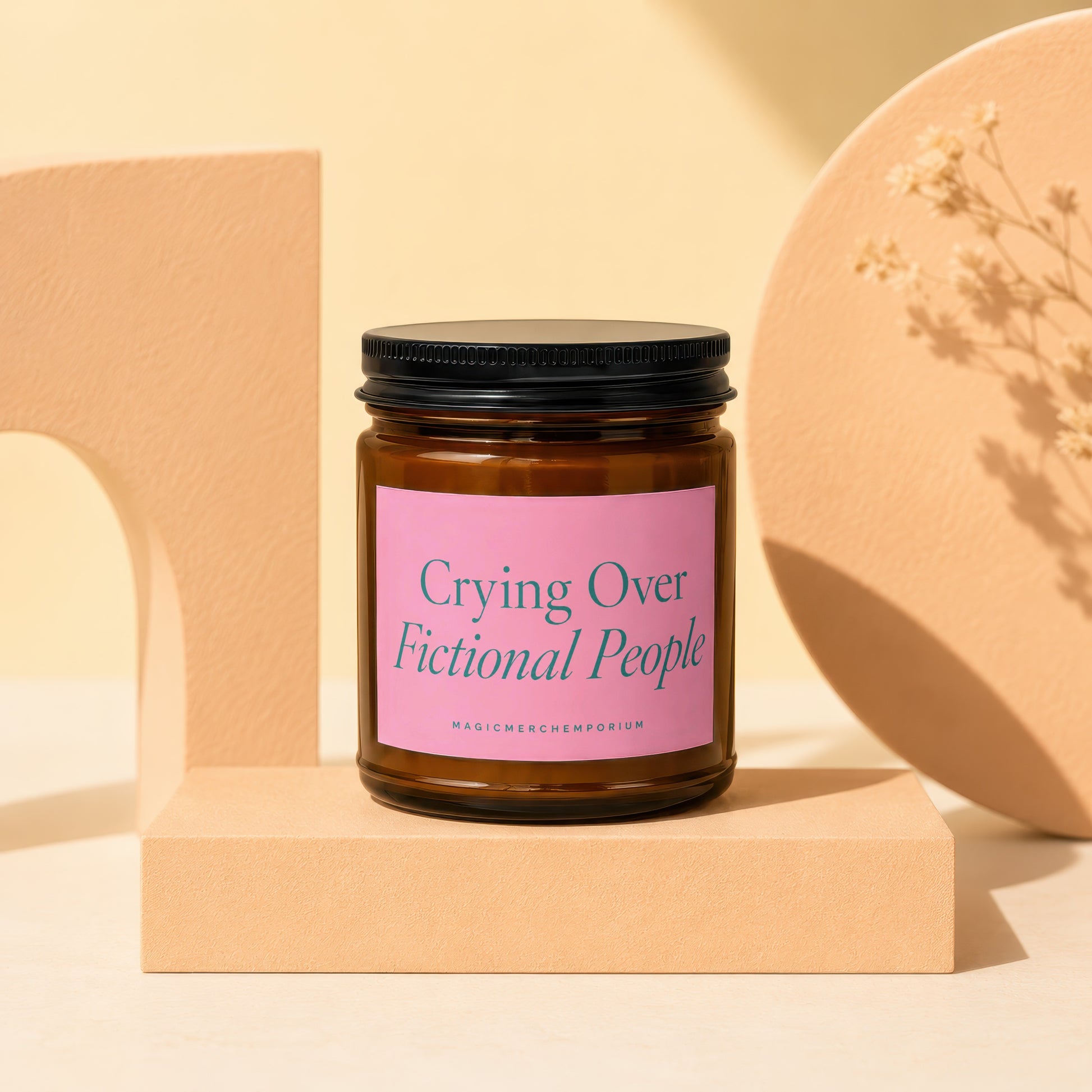 Amber jar candle with pink label reading "Crying Over Fictional People".