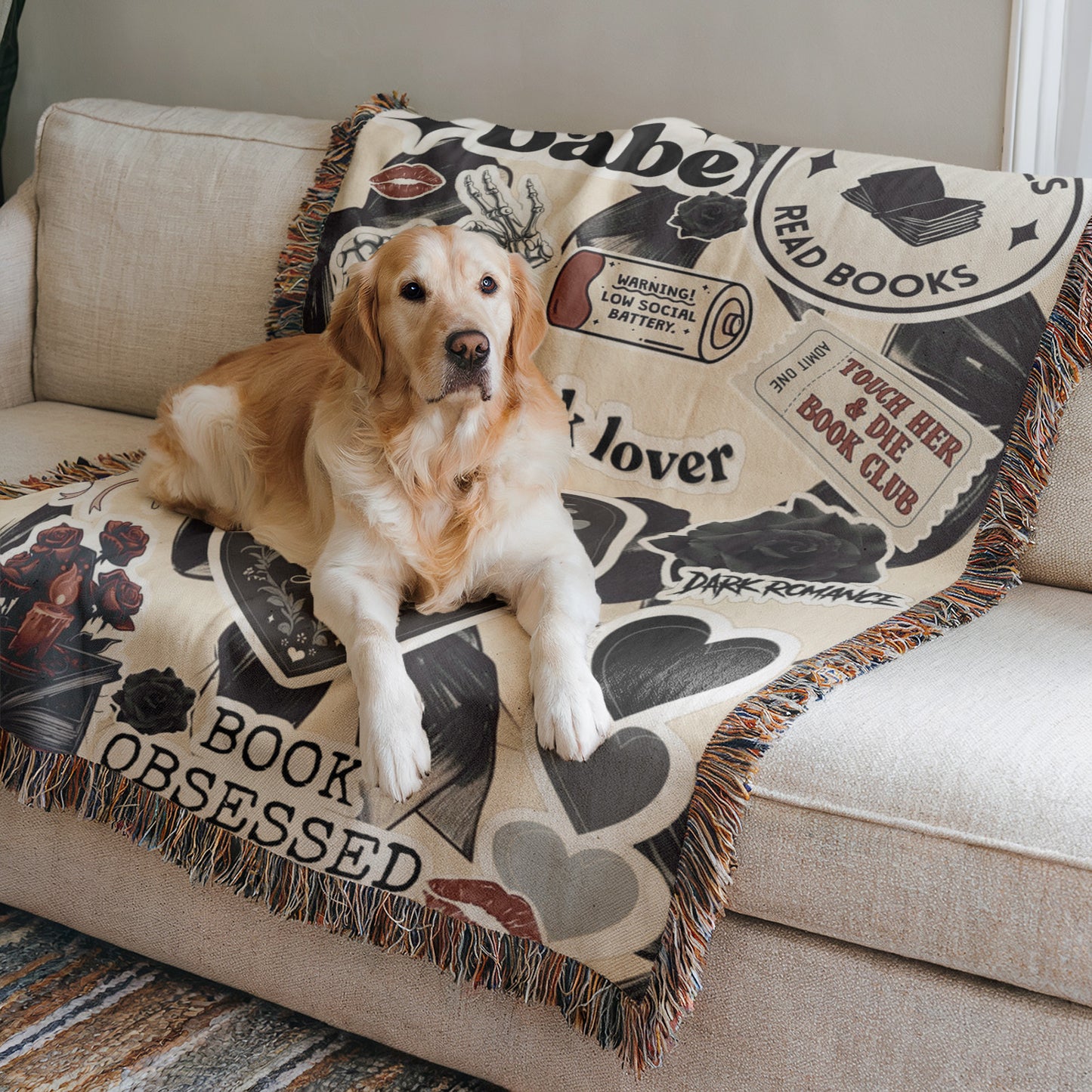 A golden retriever dog is lying on a couch with a blanket featuring various book-related designs, including a book club, a book lover, and a book.