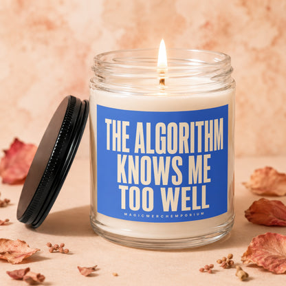 Glass jar candle with lit wick and blue label reading "THE ALGORITHM KNOWS ME TOO WELL".